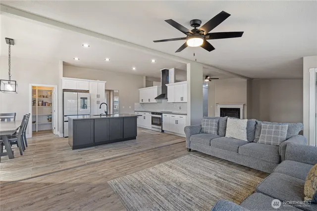 a living room with furniture kitchen view and a wooden floor