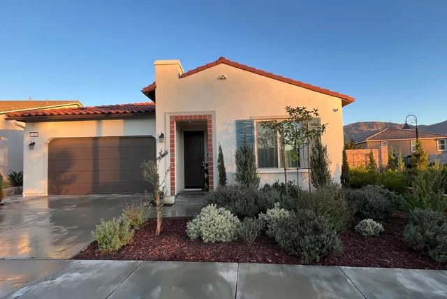 a view of a white house with potted plants