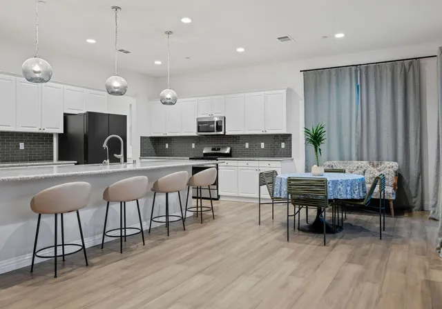a kitchen with stainless steel appliances granite countertop a table chairs sink and cabinets