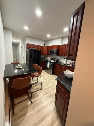 a living room with stainless steel appliances furniture a rug and a kitchen view