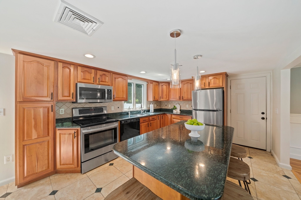 5 Kingsbury Road Canton, MA 02021 - Photo 4 of 39 a kitchen with stainless steel appliances granite countertop a refrigerator a stove top oven a sink a dining table and chairs with white cabinets