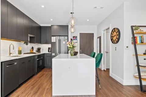 a kitchen with a refrigerator a stove top oven a clock and wooden floor