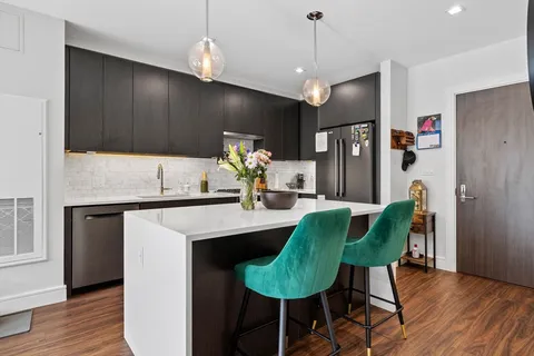 a kitchen with kitchen island a dining table chairs stainless steel appliances and wooden floor