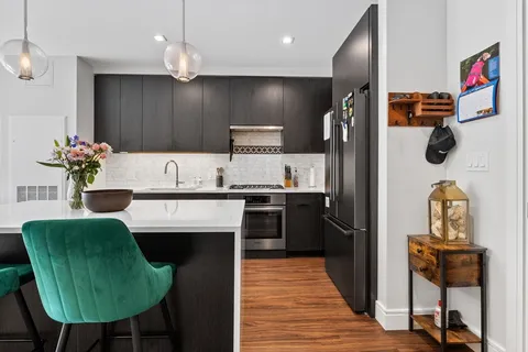 a kitchen with kitchen island stainless steel appliances a sink cabinets and wooden floor