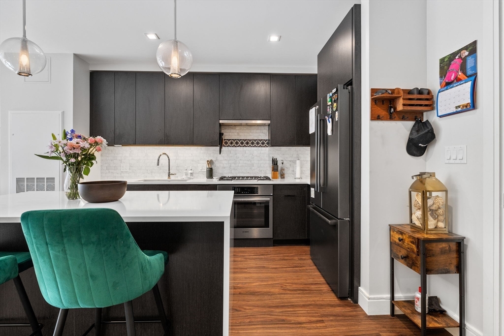 99 Sumner Street, Unit 101 Boston, MA 02128 - Photo 8 of 35 a kitchen with kitchen island stainless steel appliances a sink cabinets and wooden floor