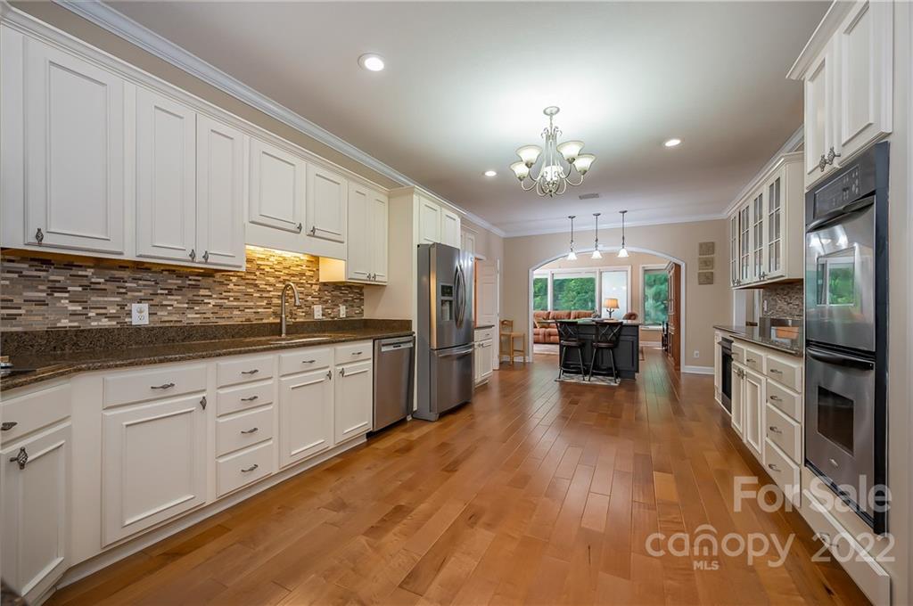 259 Bent Tree Drive Rutherfordton, NC 28139 - Photo 5 of 48 a kitchen with granite countertop a stove a sink dishwasher a refrigerator and white cabinets with wooden floor