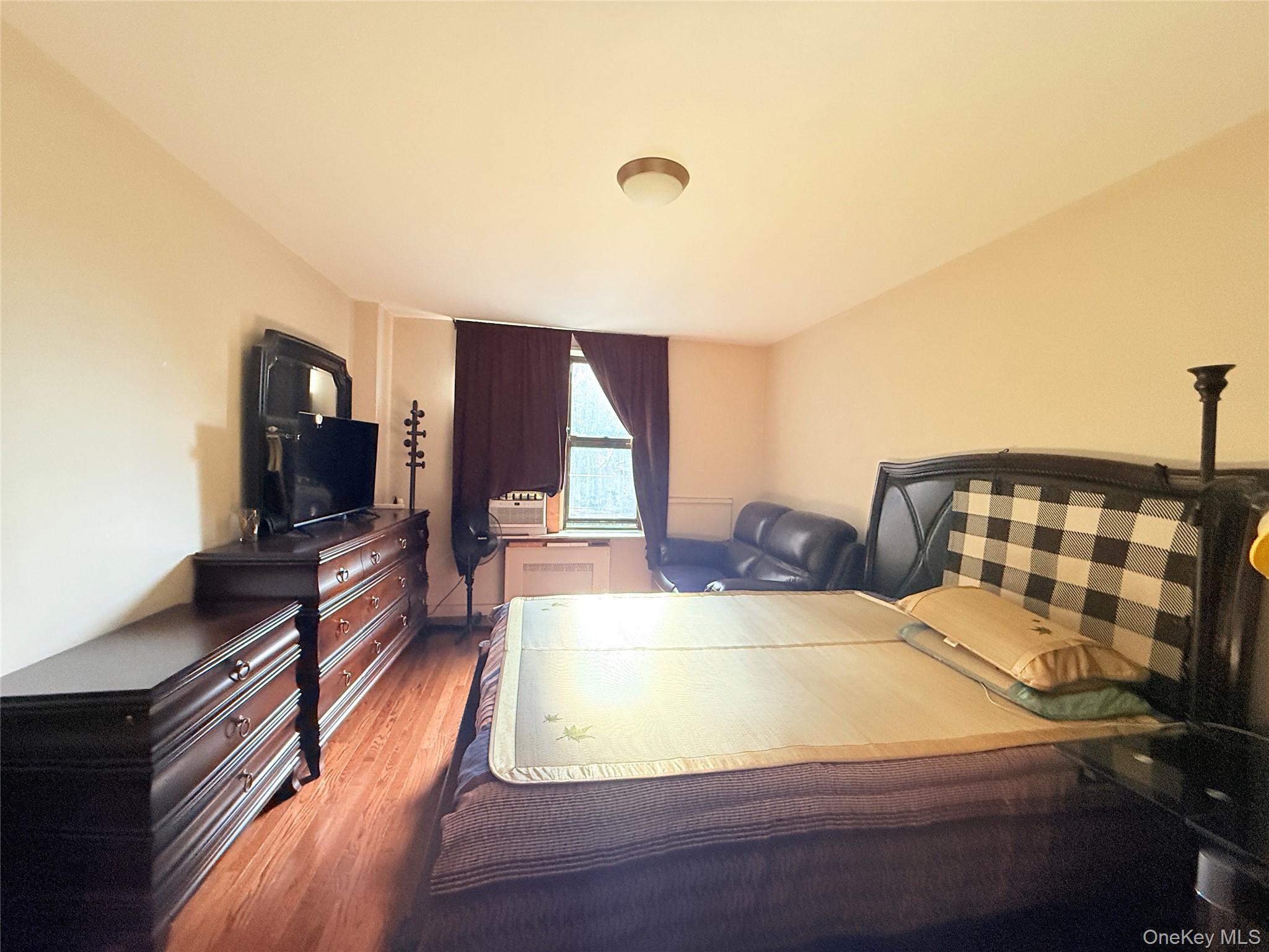 87-10 51st Avenue, Unit 5H Queens, NY 11373 - Photo 7 of 16 a bedroom with a bed and a flat screen tv