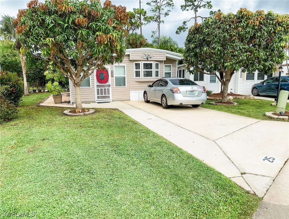 10849 Barred Owl Circle, Unit 25 Estero, FL 33928 - Photo 1 of 24 a front view of a house with a garden and trees