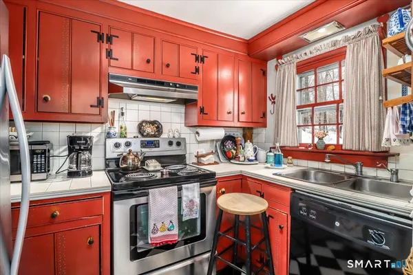 a kitchen with stainless steel appliances granite countertop a stove top oven a sink dishwasher and cabinets with wooden floor