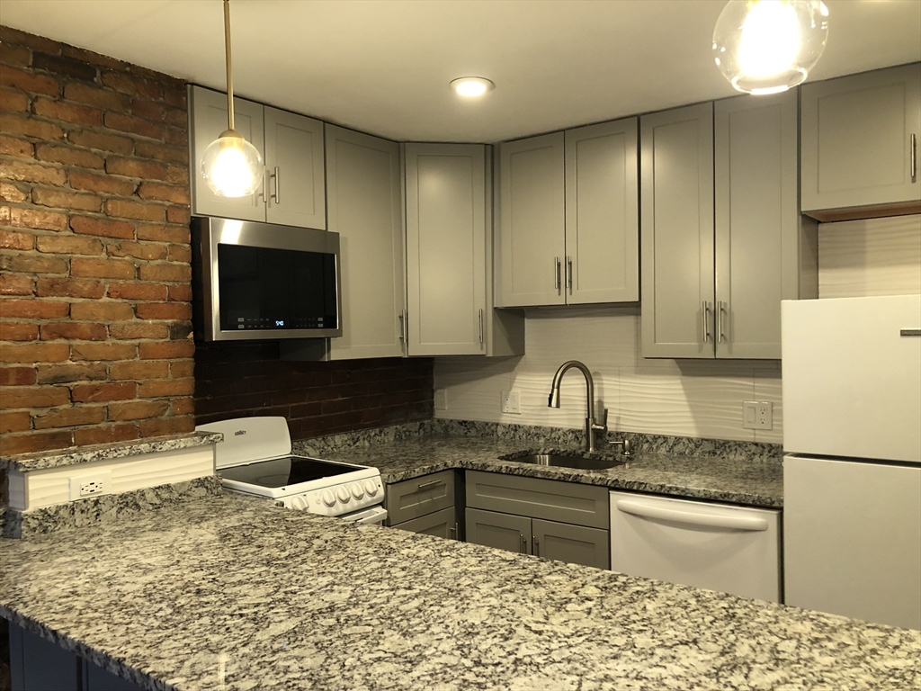 24 Bradford Street, Unit 2 Boston, MA 02118 - Photo 3 of 16 a kitchen with stainless steel appliances granite countertop a sink stove and refrigerator