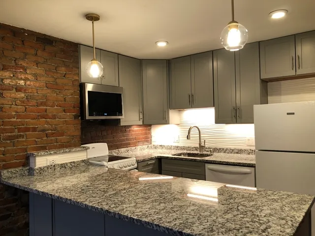 a kitchen with kitchen island granite countertop a sink and a stove