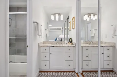 a bathroom with a granite countertop sink a mirror and a shower