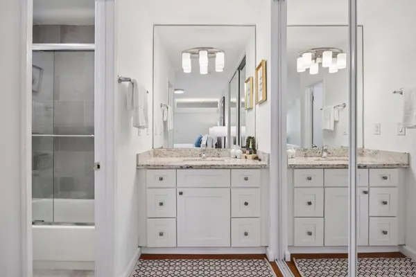 a bathroom with a granite countertop sink a mirror and a shower