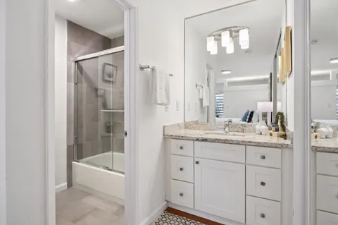 a bathroom with a granite countertop sink a mirror and a bathtub