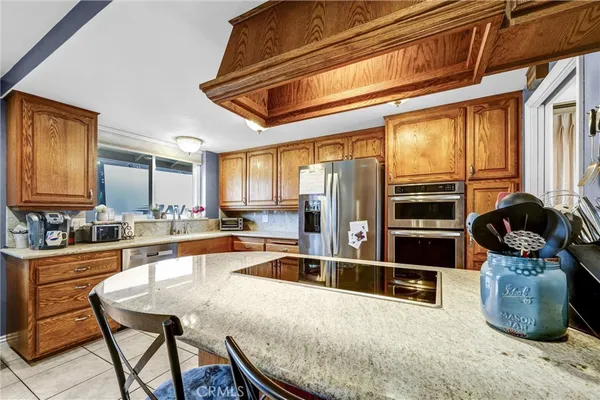 a kitchen with stainless steel appliances kitchen island granite countertop a table chairs in it and wooden floors
