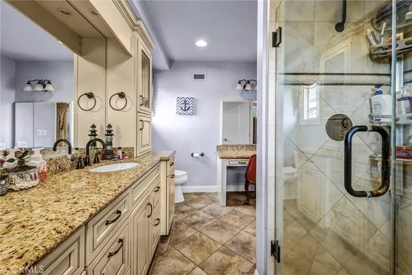 a bathroom with a granite countertop sink toilet and mirror