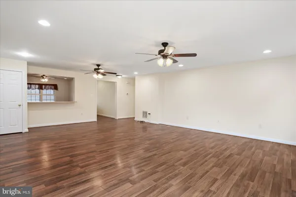 an empty room with wooden floor chandelier fan and windows