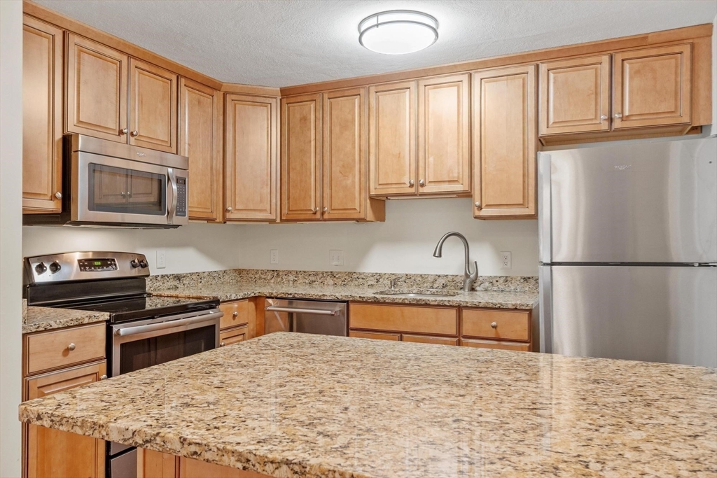 420 Great Road, Unit C1 Acton, MA 01720 - Photo 8 of 29 a kitchen with granite countertop a refrigerator sink stove and microwave