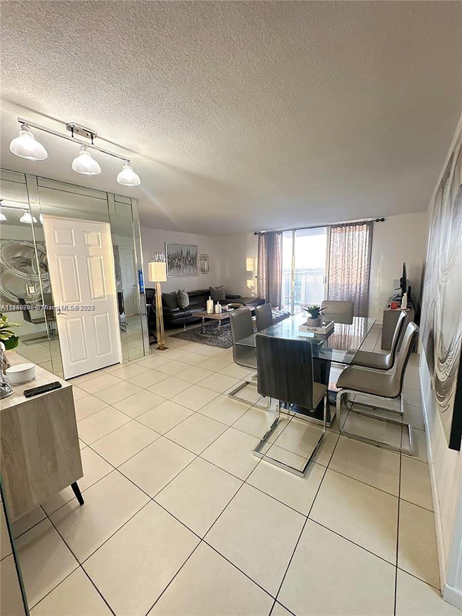 2750 Northeast 183rd Street, Unit 1404 Aventura, FL 33160 - Photo 5 of 14 a living room with furniture a dining table and a stove top oven