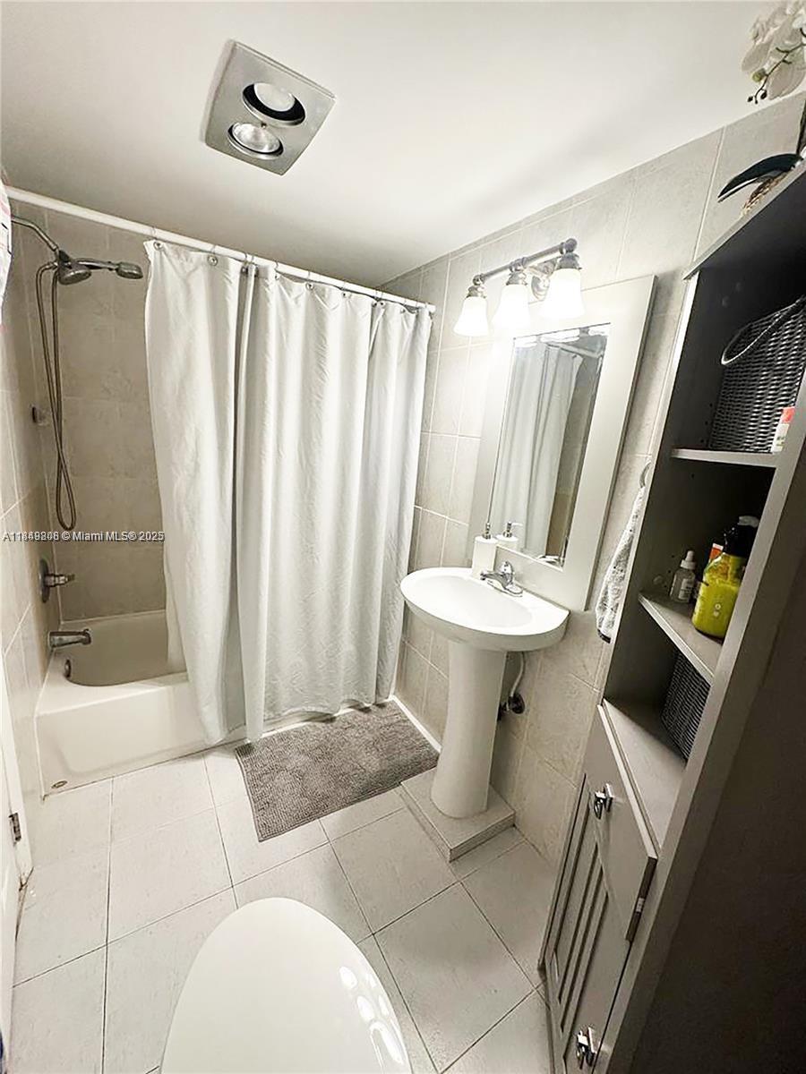2750 Northeast 183rd Street, Unit 1404 Aventura, FL 33160 - Photo 10 of 14 a bathroom with a sink a mirror and a shower