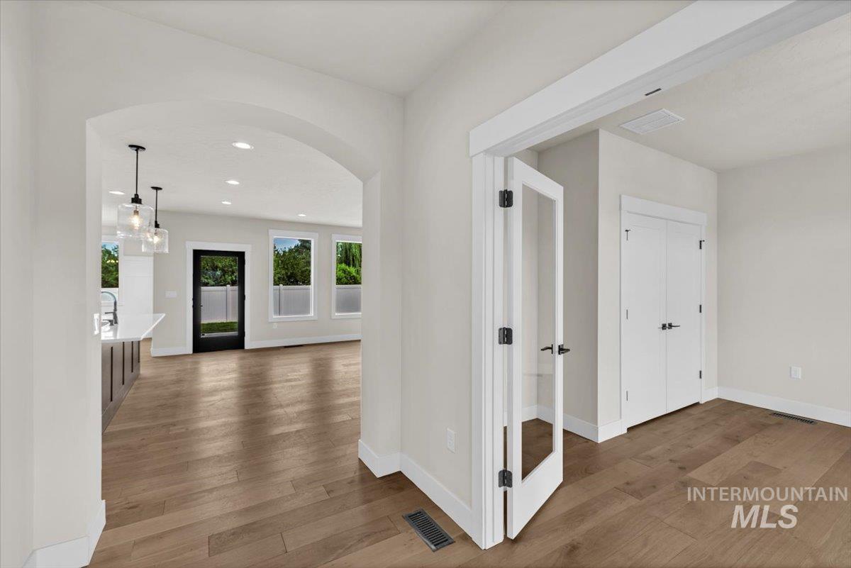72 South Ravine Way Nampa, ID 83687 - Photo 5 of 48 Open-concept interior featuring wood-finish flooring, an arched entryway, recessed lighting, a kitchen island with pendant lighting, and a room with French doors