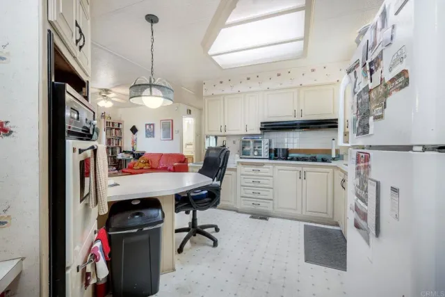 a kitchen with stainless steel appliances a white table chairs and a refrigerator