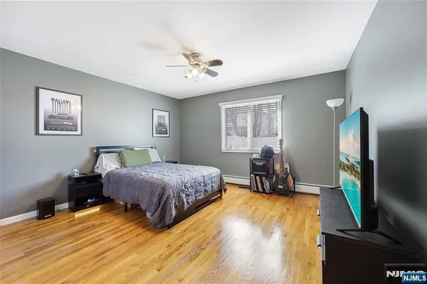 a spacious bedroom with a bed table closet and a flat tv screen on a dresser