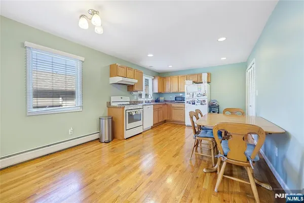 a kitchen with stainless steel appliances granite countertop a stove top oven a sink dishwasher and white cabinets with wooden floor