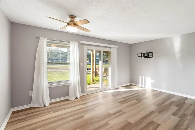 a view of an empty room with a window and wooden floor