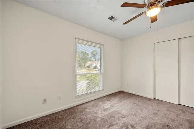 an empty room with a window and ceiling fan