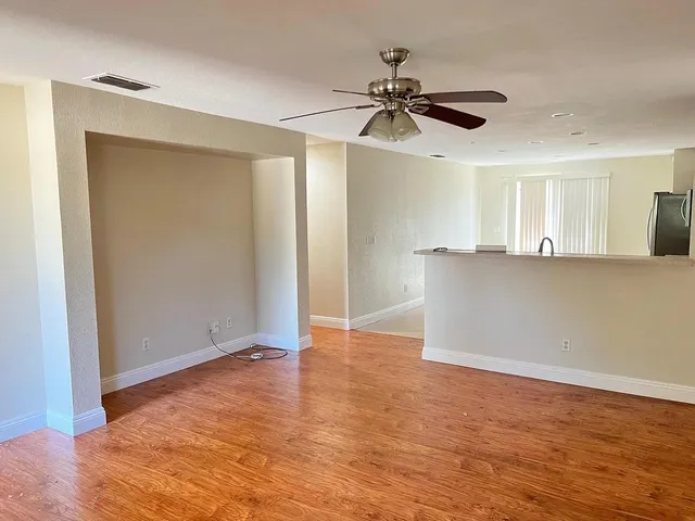 an empty room with wooden floor closet and windows
