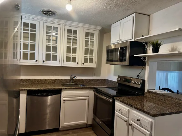 a kitchen with stainless steel appliances granite countertop a sink stove and microwave