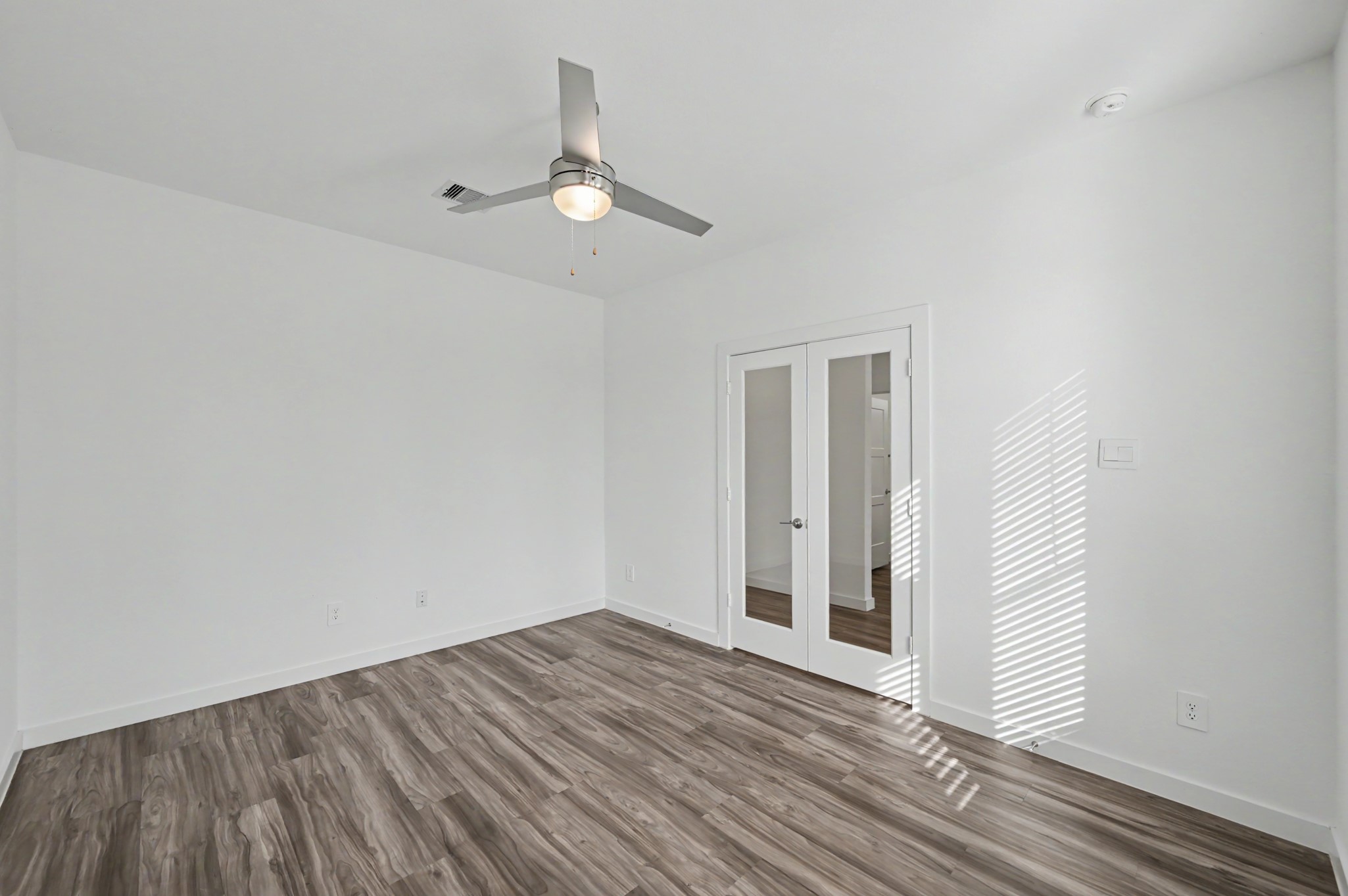 14162 Primrose Ridge Lane Conroe, TX 77384 - Photo 7 of 48 Bright and airy room featuring sleek wood flooring, a modern ceiling fan, and elegant French doors that enhance the space with natural light.
