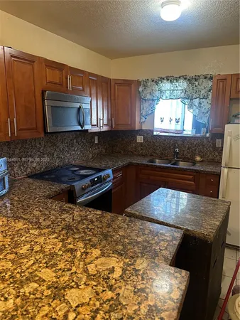 a kitchen with stainless steel appliances kitchen island granite countertop a stove a sink and a microwave