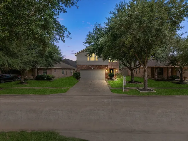 a view of a house with a yard and large trees
