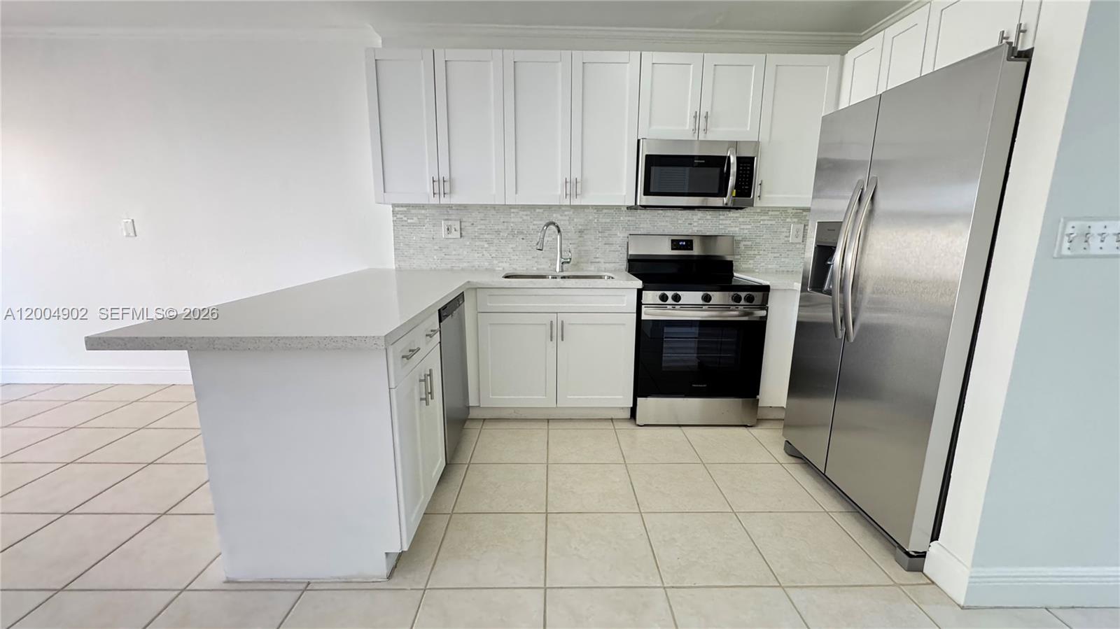 9465 Southwest 77th Court Miami, FL 33156 - Photo 14 of 25 a kitchen with a sink a microwave and refrigerator