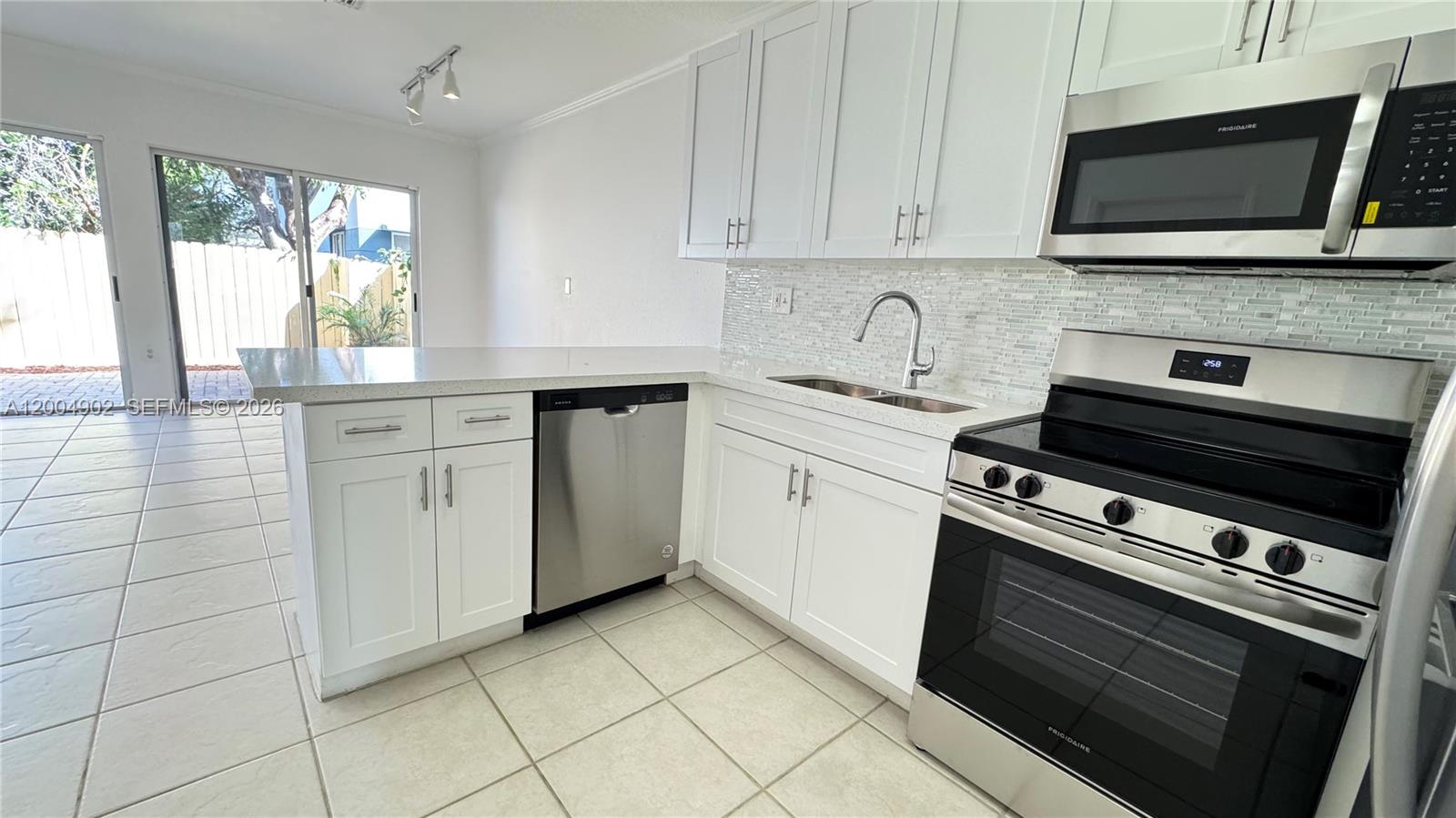 9465 Southwest 77th Court Miami, FL 33156 - Photo 15 of 25 a kitchen with granite countertop a stove top oven cabinetry a sink and a microwave