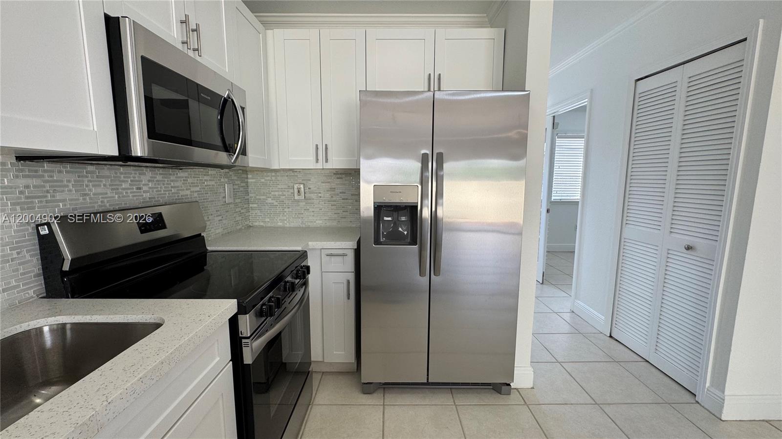 9465 Southwest 77th Court Miami, FL 33156 - Photo 16 of 25 a kitchen with granite countertop a refrigerator and a sink