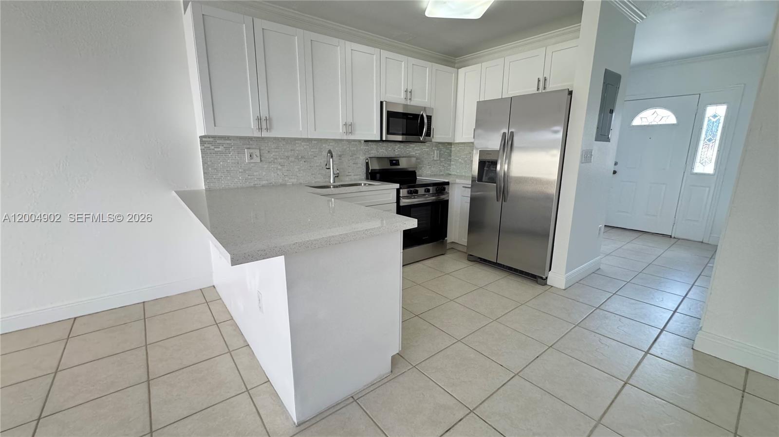 9465 Southwest 77th Court Miami, FL 33156 - Photo 9 of 25 a kitchen with stainless steel appliances granite countertop a refrigerator a stove a sink and a microwave