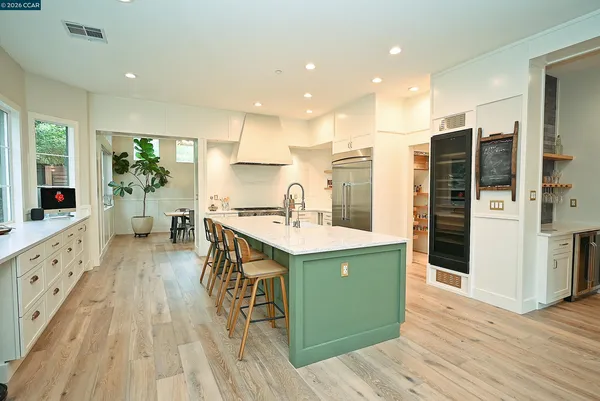 a kitchen with stainless steel appliances kitchen island granite countertop a table chairs refrigerator and sink