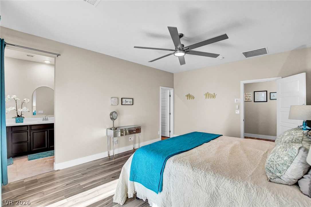 9688 Rankin Rdg Court Las Vegas, NV 89178 - Photo 36 of 53 A comfortable bedroom features a contemporary ceiling fan, opening to an adjacent private bathroom with vanity.