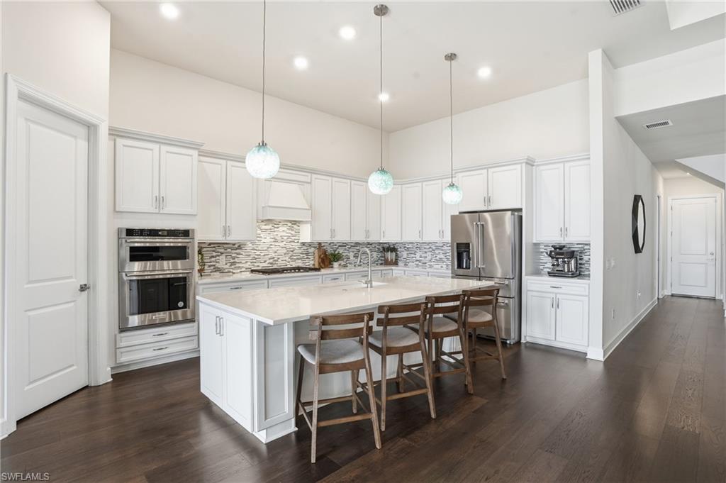 19696 Aqua View Lane Fort Myers, FL 33913 - Photo 12 of 50 a kitchen with stainless steel appliances kitchen island granite countertop a wooden floor and white cabinets