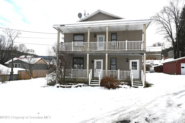 a front view of a house with a yard covered in snow