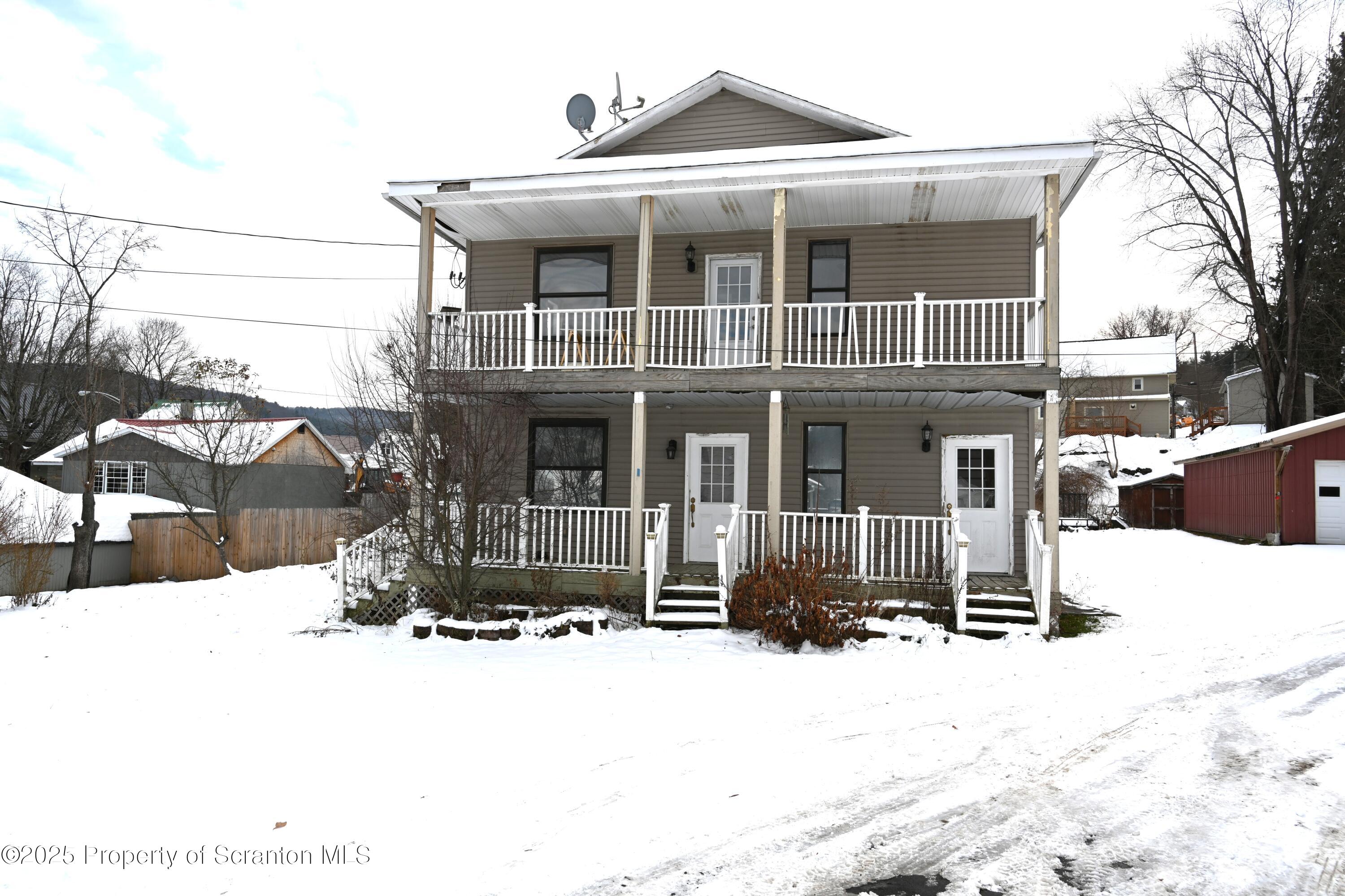 a front view of a house with a yard covered in snow