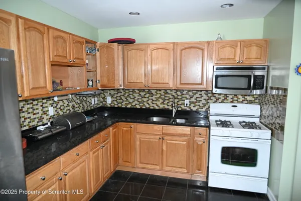 a kitchen with granite countertop a sink stove and microwave