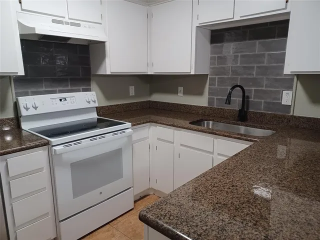 a kitchen with granite countertop a stove and a sink