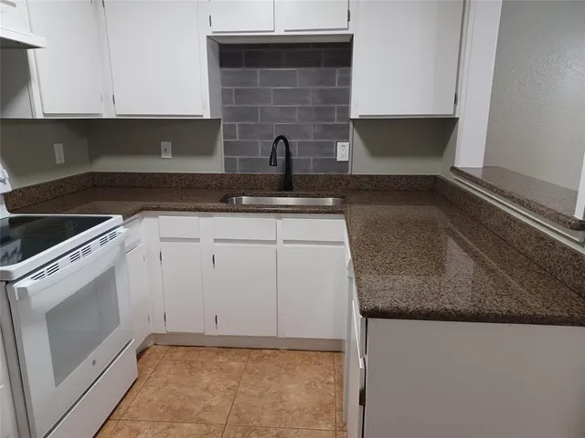 a kitchen with granite countertop a sink and a stove