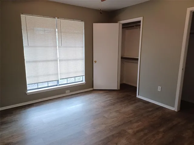 an empty room with wooden floor cabinet and windows
