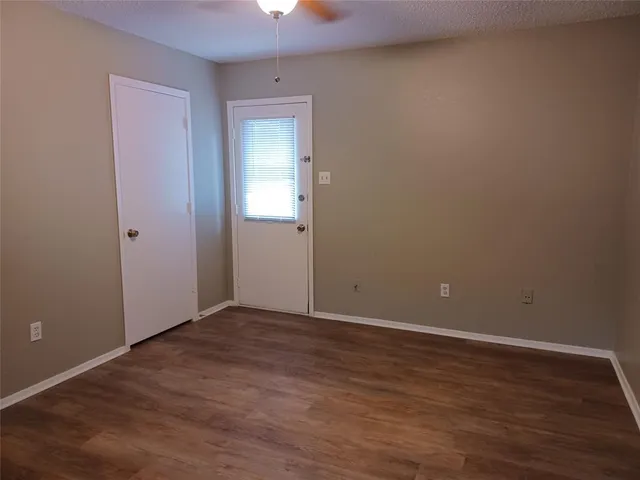 a view of an empty room with wooden floor and closet