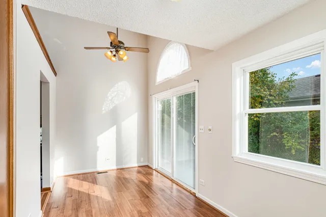 a view of empty room with wooden floor and fan